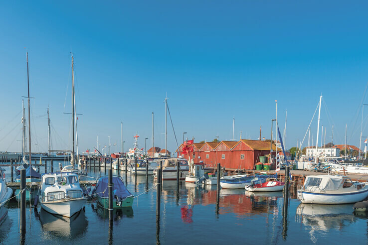 Laboe harbour festival Sailing boats in the harbor in front of red wooden houses, blue sky, calm water.