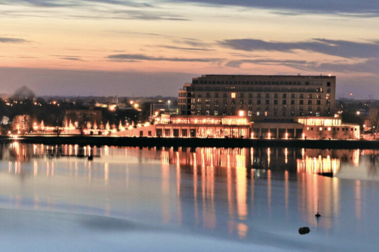 The ATLANTIC Hotel Wilhelmshaven at the Great Harbour Large hotel on the water at sunset, illuminated, with reflection in the calm lake.