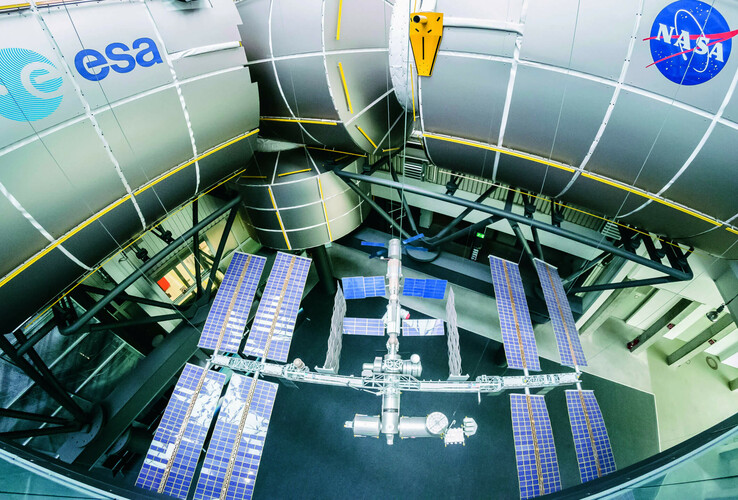 guided tours Model of the International Space Station with solar panels, surrounded by large metal structures with ESA and NASA logos.