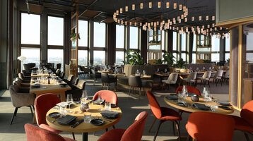 Restaurant 15 High on the 15th floor of the ATLANTIC Hotel Heidelberg Modern hotel restaurant with elegant wooden tables, red and gray chairs, large windows and stylish hanging lamps.