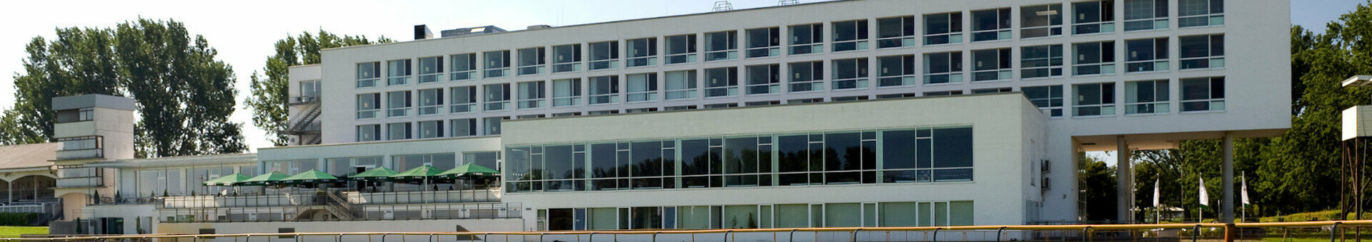 ATLANTIC Hotel on the Galopprennbahn ATLANTIC Hotel Galopprennbahn, modern building with large windows, surrounded by green lawns and trees.