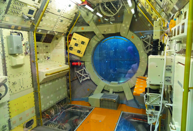 guided tours, space lab Interior of a space station with technical equipment and a large round window showing the view into space.