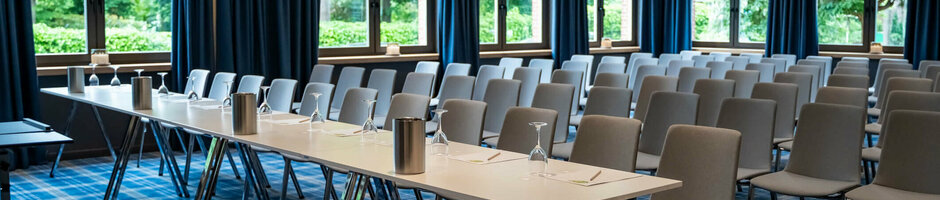 Modern conference room with blue curtains, tables and chairs at the ATLANTIC Hotel Landgut Horn Bremen.