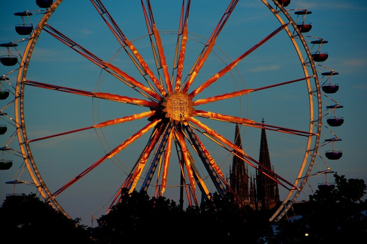 Dult ferris wheel Ferris wheel in the evening light against a blue sky, with the spires of a Gothic cathedral in the background.