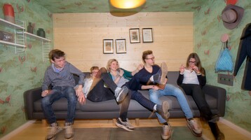 Teenager on a sofa for the campaign "Breakfast special" of the ATLANTIC Hotel Universum Five people are sitting happily on a sofa in a colorfully decorated room.