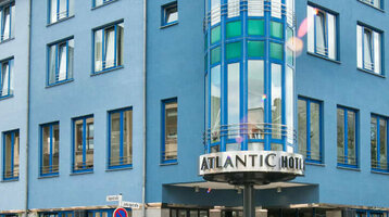 ATLANTIC Hotel Vegesack Bremen Exterior view of the ATLANTIC Hotel Vegesack in Bremen with blue façade and striking glass tower in daylight.