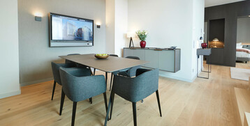 Executive Suite dining area in the ATLANTIC Grand Hotel Bremen Modern conference room with table, four chairs, wall screen and stylish decoration at the ATLANTIC Grand Hotel Bremen.
