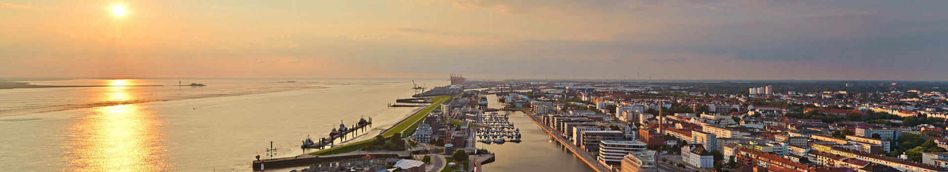 Aussicht auf den neuen Hafen in Bremerhaven Blick auf Bremerhaven vom ATLANTIC Hotel Sail City bei Sonnenuntergang, mit Hafen, Fluss und Stadtpanorama.