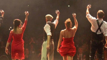 Magic Moments offer at the ATLANTIC Hotel Münster with admission to the GOP Varieté Theatre A group of eight artists solemnly raise glasses on a stage in front of an applauding audience.