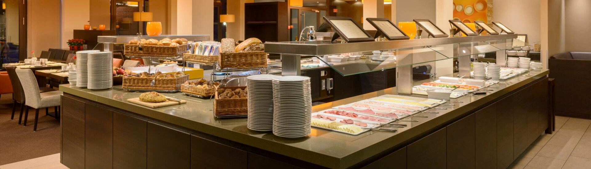 Modern breakfast buffet at the ATLANTIC Hotel Lübeck with bread, cold cuts, fruit and crockery in an elegant ambience.