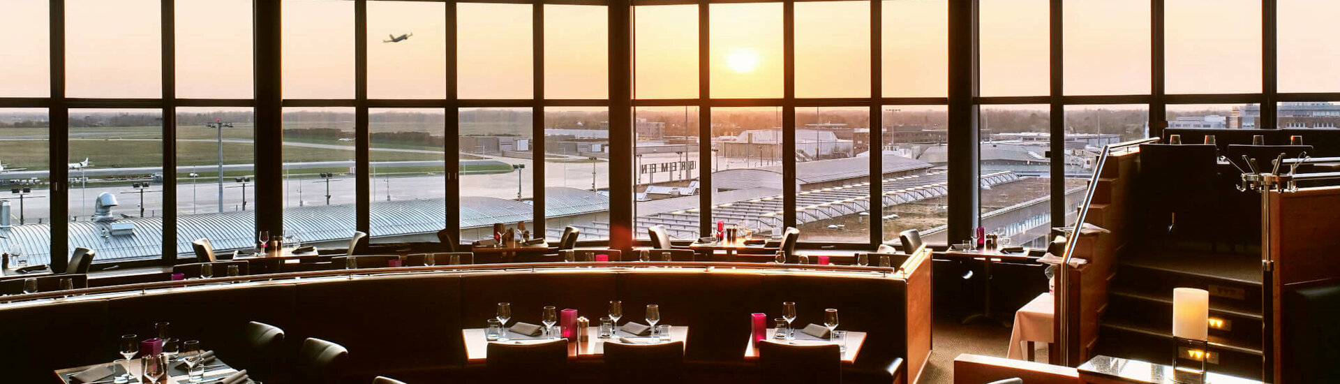 Restaurant Blixx in the ATLANTIC Hotel Airport in Bremen Restaurant with panoramic windows, view of the airport and sunset, elegantly laid tables at the ATLANTIC Hotel Airport Bremen.