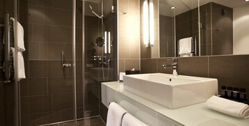 Bathroom of the Executive Room in the ATLANTIC Grand Hotel in Bremen Modern bathroom with walk-in shower, large washbasin and stylish lighting at the ATLANTIC Grand Hotel Bremen.