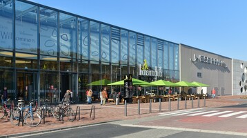 View of the shopping centre Weserpark in Bremen Modern glass façade of the Weserpark in Bremen with outdoor seating area and bicycle racks.