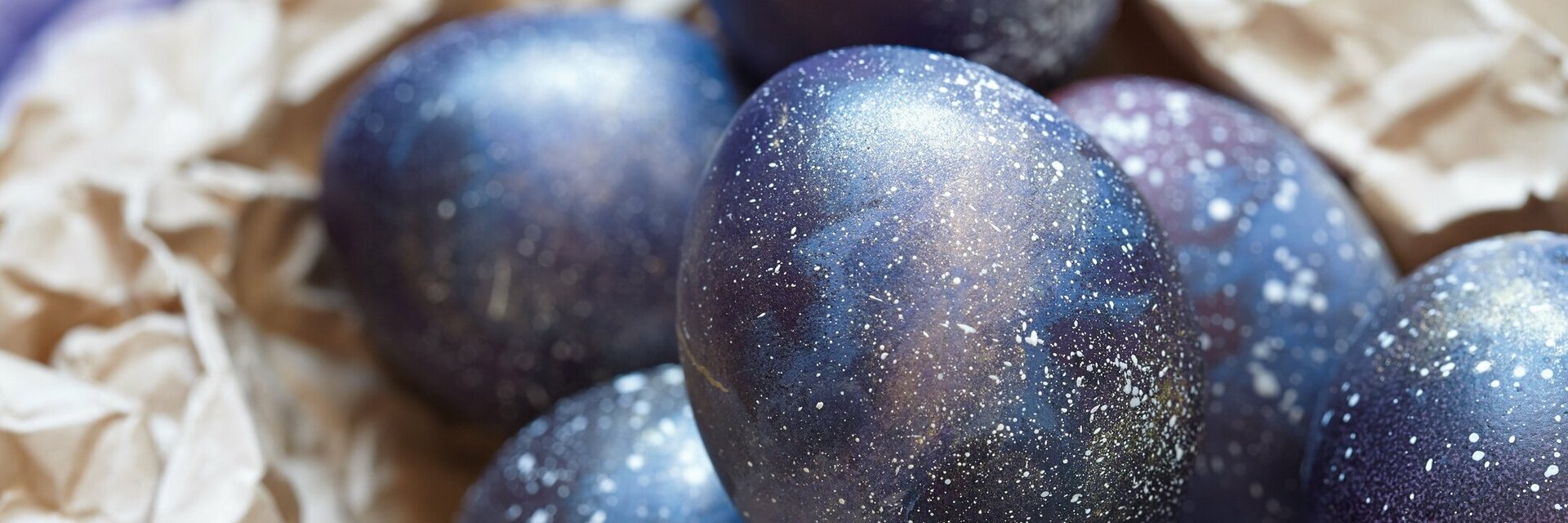 Dunkelblau gefärbte Ostereier liegen auf braunem Packpapier.