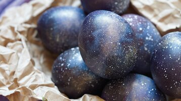 Dark blue Easter eggs lie on brown wrapping paper.