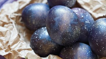 Dunkelblau gefärbte Ostereier liegen auf braunem Packpapier.