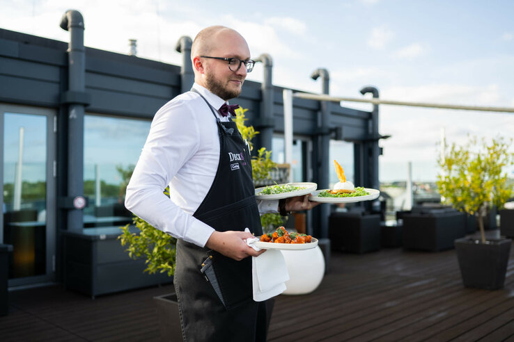 ATLANTIC Hotel Kiel Deck 8 A friendly waiter serves food on the roof terrace of Bar Deck 8 Kiel