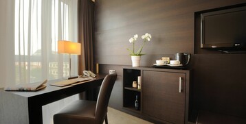 Desk and TV in the superior room of the ATLANTIC Grand Hotel in the city centre of Bremen Modern hotel room with desk, chair, lamp, orchid and television in the ATLANTIC Grand Hotel Bremen.