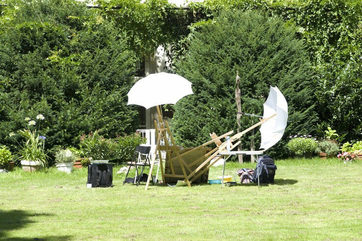 Knoops Park Bremen Garden with green lawn, chairs, white parasols and lush bushes in the background.