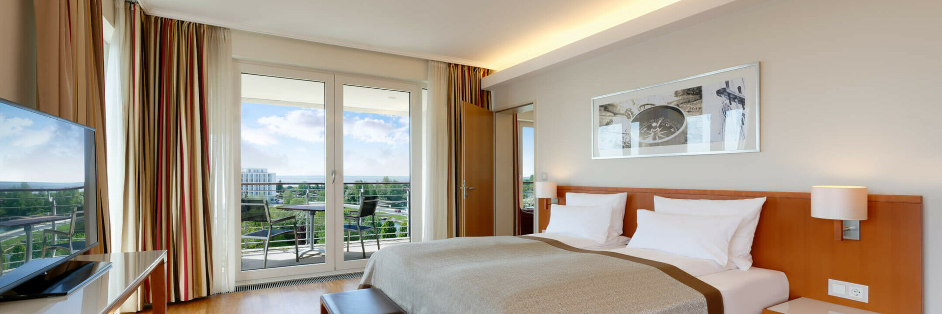 Special offer 5 for 4 nights Bright hotel room with double bed, wooden floor, TV, balcony with chairs and view of the green landscape.