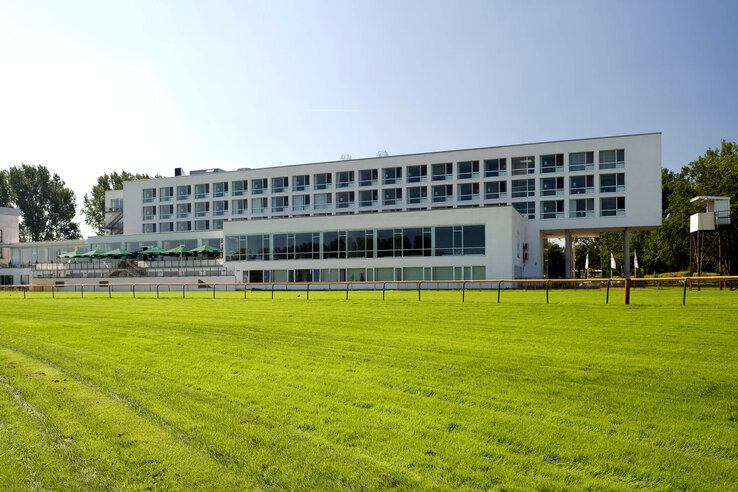ATLANTIC Hotel Galopprennbahn in Bremen ATLANTIC Hotel Galopprennbahn: Modernes Gebäude mit großen Fenstern, umgeben von grüner Rasenfläche.