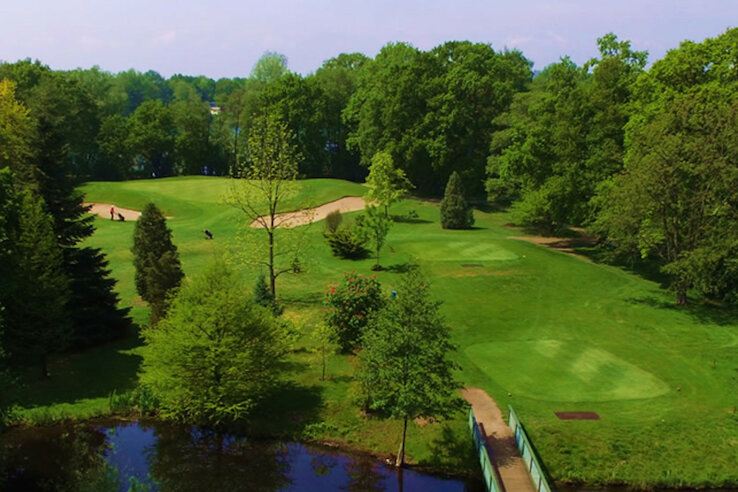 Golf Course in Oberneuland | ATLANTIC Hotel Landgut Horn Golf course with green fairways, sand bunkers, trees and a small pond in the foreground.