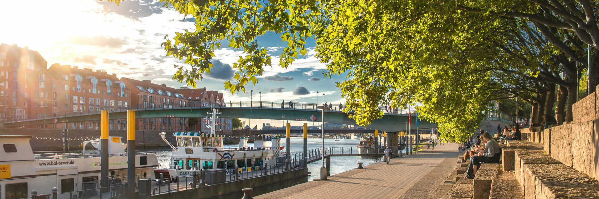 ATLANTIC Grand Hotel Bremen Schlachte im Frühling Sonniger Spazierweg an der Weser mit Blick auf Boote, Brücke und Bäume, nahe dem ATLANTIC Grand Hotel Bremen.