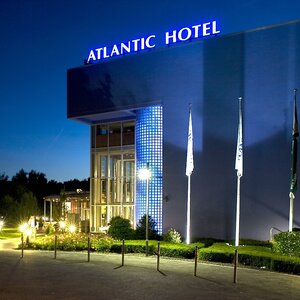 Außenansicht des ATLANTIC Hotel Universum Bremen bei Nacht ATLANTIC Hotel Universum bei Nacht, beleuchtete Fassade, drei Fahnenmasten, gepflegter Eingangsbereich.