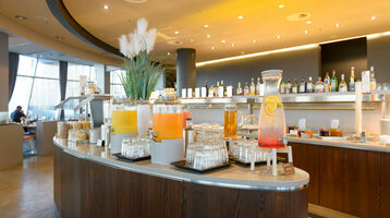 Breakfast in the Restaurant Strom | ATLANTIC Hotel Sail City Drinks bar in the ATLANTIC Hotel Sail City with juice dispensers and glasses, modern interior in the background.